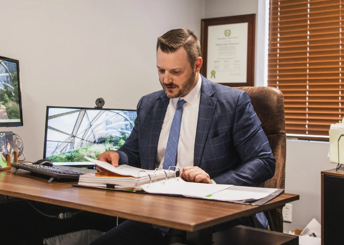 Portrait of Matt Zimmerman, Partner at Blizzard & Zimmerman Attorneys in Abilene, Texas working at his desk. He is wearing a dark suit with a light dress-shirt and a subtle tie, his hair neatly styled. He looks confidently into the camera with a calm, approachable expression—reflecting his role helping clients in family law, civil litigation, probate and estate planning.